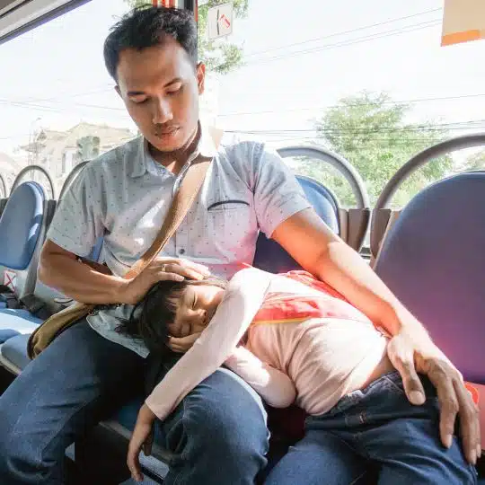 Un padre asiático se sienta en el autobús con su hija pequeña